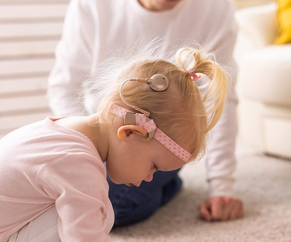 Kid with cochlear implants playing with toys at home. Deafness and medical technology